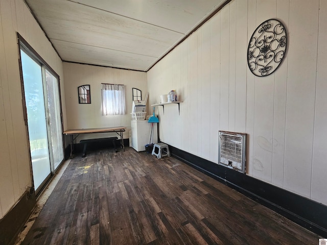 empty room featuring wood walls, heating unit, and hardwood / wood-style floors