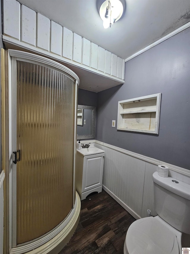 bathroom featuring walk in shower, hardwood / wood-style flooring, toilet, wood walls, and vanity