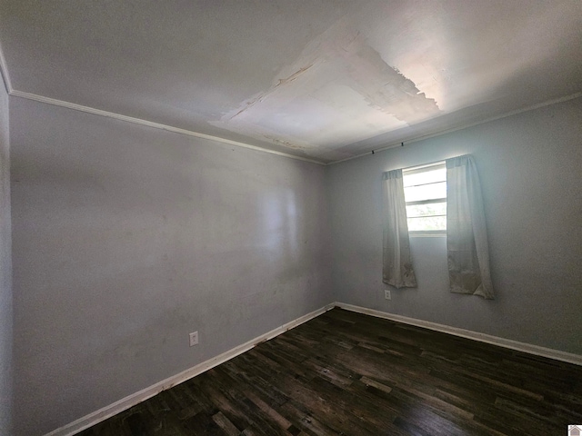 spare room featuring dark wood-type flooring and crown molding