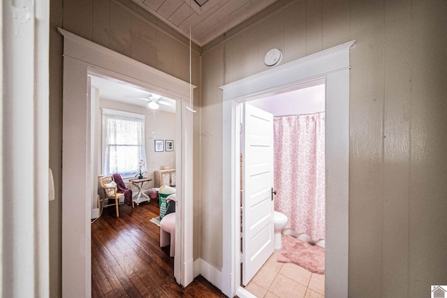 corridor featuring ornamental molding, wooden walls, and hardwood / wood-style flooring