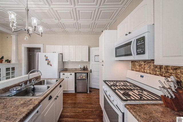 kitchen featuring dark wood-type flooring, white cabinets, hanging light fixtures, and white appliances