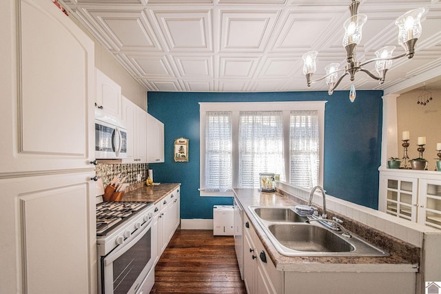 kitchen featuring white cabinets, hanging light fixtures, dark hardwood / wood-style flooring, sink, and white appliances