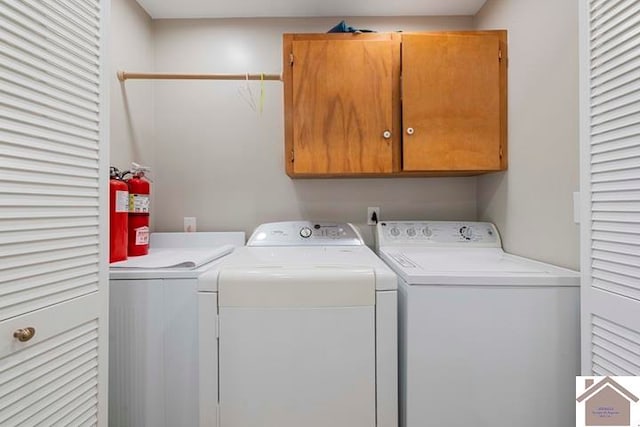 laundry area with washing machine and clothes dryer and cabinets