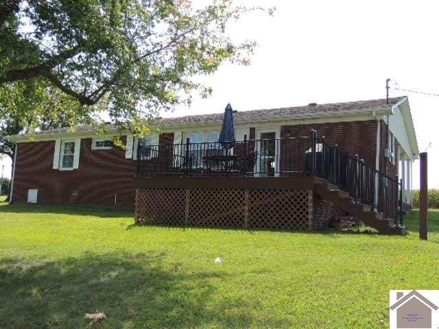 back of property featuring a wooden deck and a yard