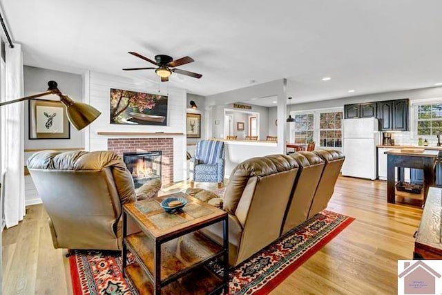 living room with a fireplace, light hardwood / wood-style floors, and ceiling fan