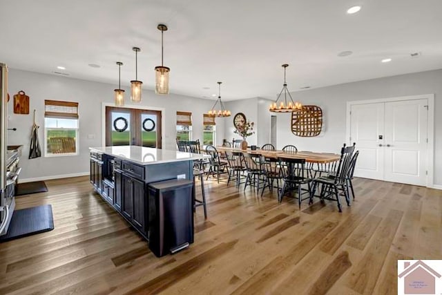 kitchen with dark hardwood / wood-style flooring, a kitchen island, a kitchen bar, a notable chandelier, and decorative light fixtures