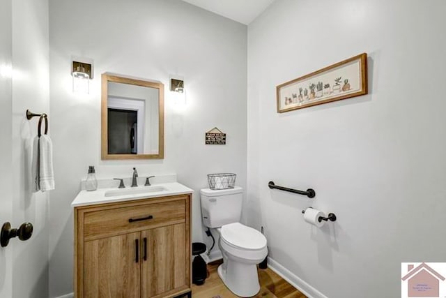 bathroom with toilet, vanity, and wood-type flooring