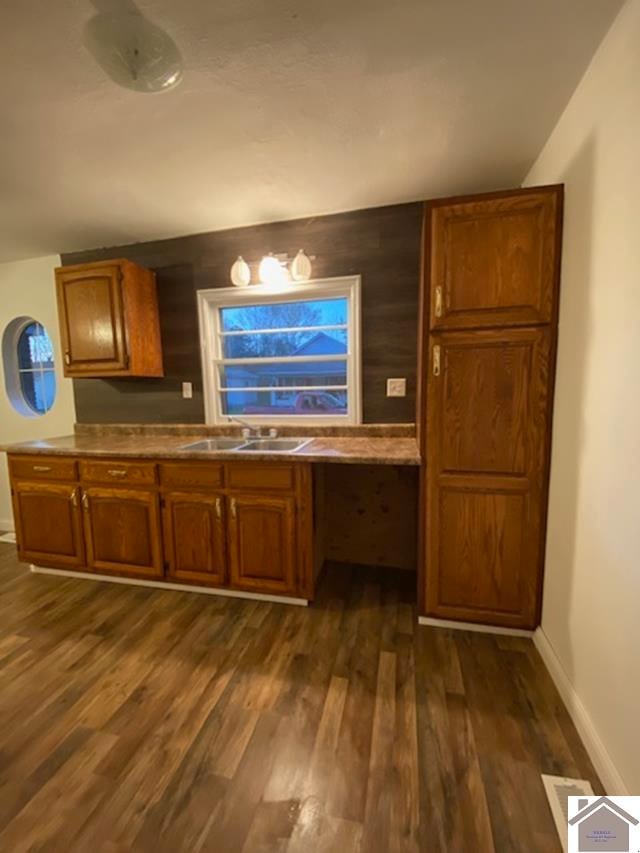 kitchen featuring sink, dark wood-type flooring, and built in desk