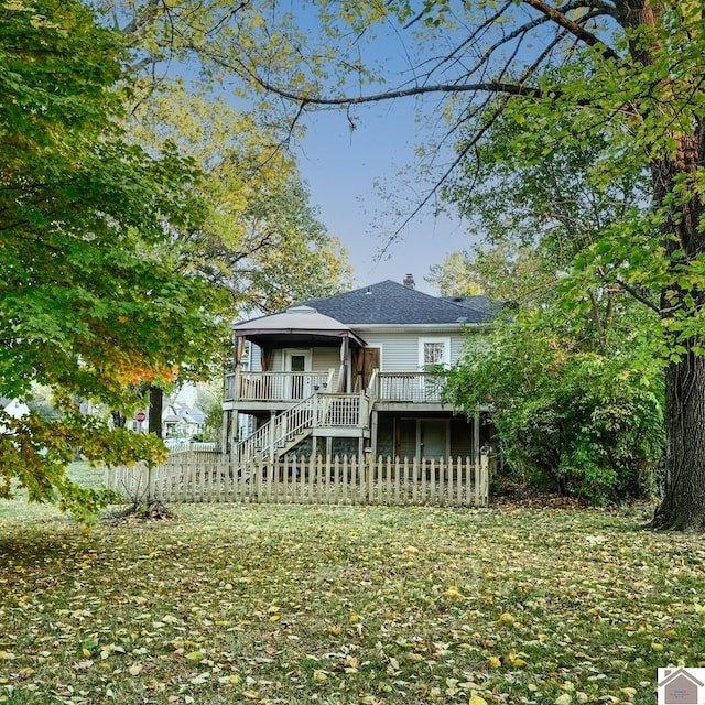 rear view of house featuring a deck and a lawn