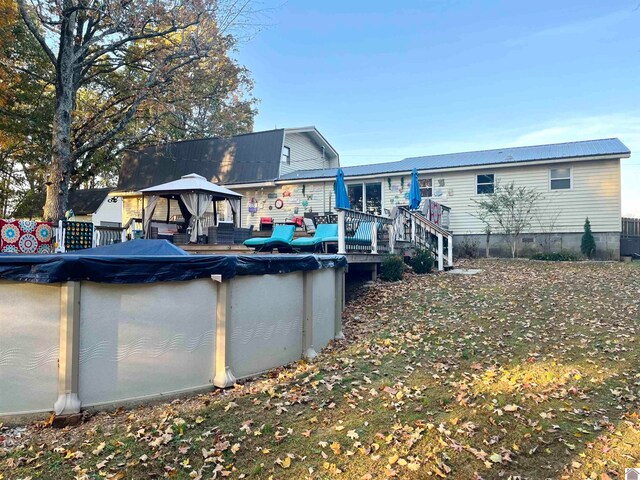 rear view of property featuring a gazebo and a pool side deck