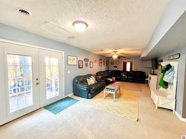 carpeted living room with ceiling fan, french doors, and a textured ceiling