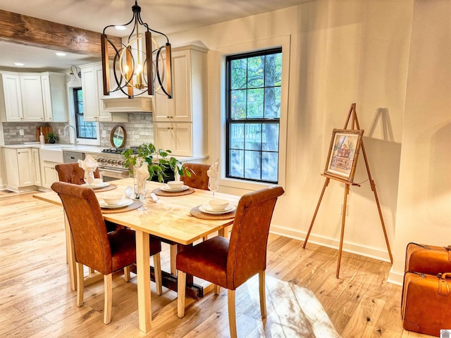 dining area featuring beam ceiling, sink, an inviting chandelier, and light wood-type flooring