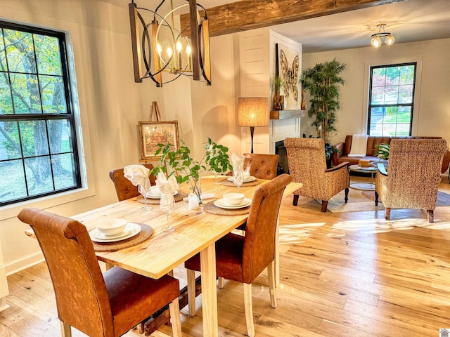 dining room featuring beamed ceiling, light hardwood / wood-style floors, and a notable chandelier