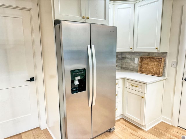 kitchen featuring stainless steel fridge with ice dispenser, backsplash, light hardwood / wood-style floors, and white cabinetry