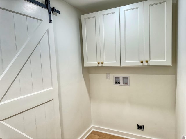 washroom with cabinets, washer hookup, electric dryer hookup, a barn door, and light hardwood / wood-style flooring