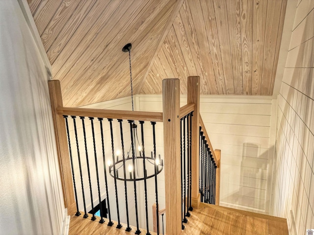 stairway with wood ceiling, wooden walls, wood-type flooring, and a notable chandelier