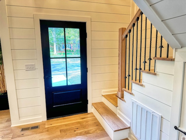 entryway featuring light wood-type flooring and wooden walls