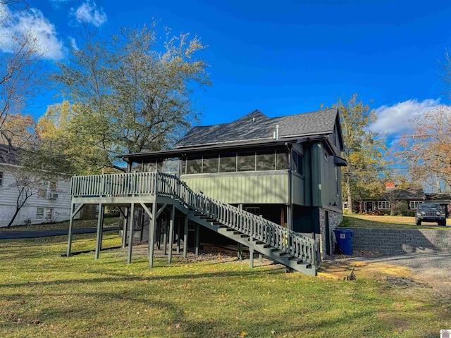 rear view of house featuring a deck, a lawn, and a sunroom