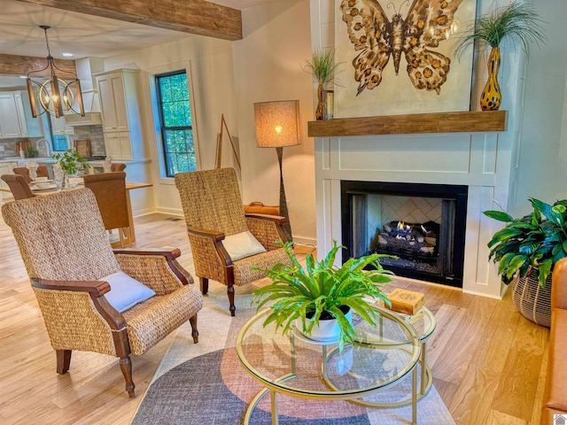 sitting room featuring a chandelier, beamed ceiling, and light hardwood / wood-style floors