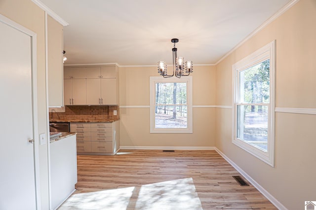 kitchen featuring decorative backsplash, crown molding, pendant lighting, and light hardwood / wood-style floors