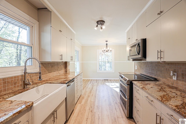 kitchen with a healthy amount of sunlight, tasteful backsplash, appliances with stainless steel finishes, and decorative light fixtures