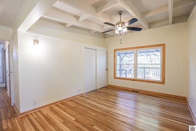 unfurnished bedroom featuring a closet, ceiling fan, wood-type flooring, and beam ceiling