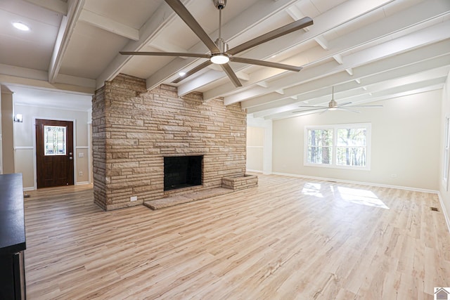 unfurnished living room with beam ceiling, a stone fireplace, light wood-type flooring, and ceiling fan