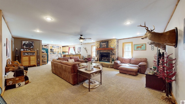 carpeted living room with crown molding, a stone fireplace, and ceiling fan