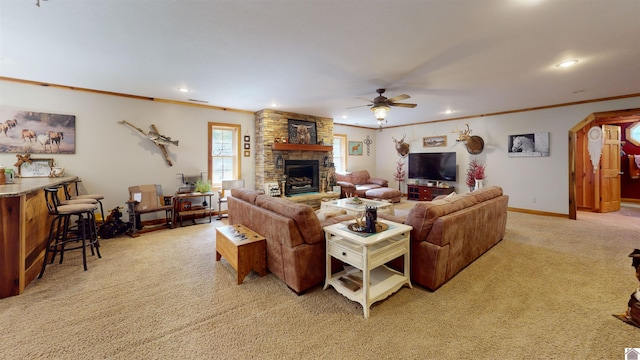 carpeted living room featuring a stone fireplace, ornamental molding, and ceiling fan