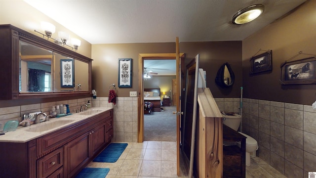 bathroom with ceiling fan, tile walls, toilet, vanity, and tile patterned floors