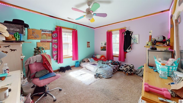 carpeted bedroom featuring crown molding, multiple windows, and ceiling fan