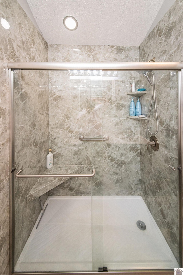 bathroom featuring a textured ceiling and a shower with shower door