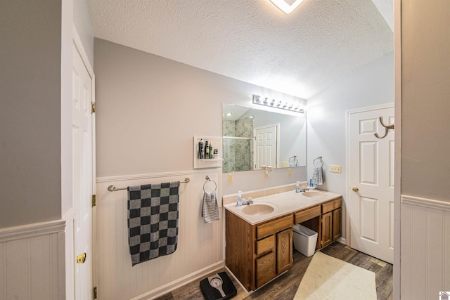 bathroom with vanity, a textured ceiling, vaulted ceiling, and hardwood / wood-style floors