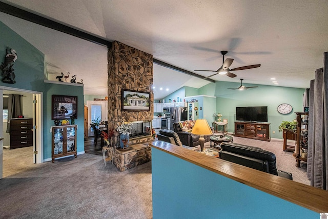 carpeted living room with vaulted ceiling, a stone fireplace, a textured ceiling, and ceiling fan