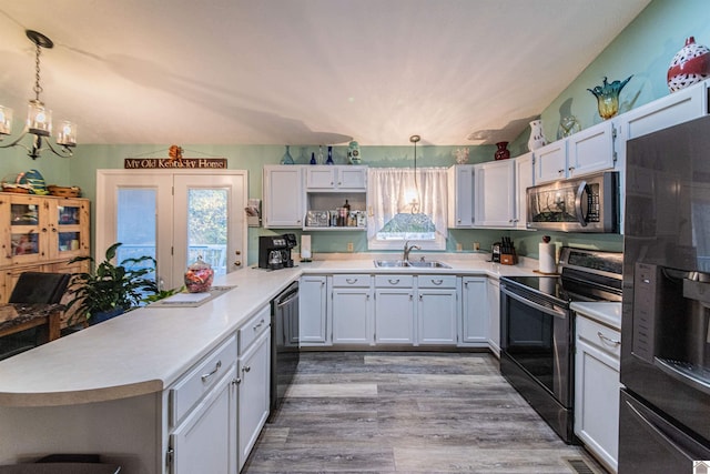 kitchen featuring white cabinetry, hardwood / wood-style flooring, black appliances, pendant lighting, and sink