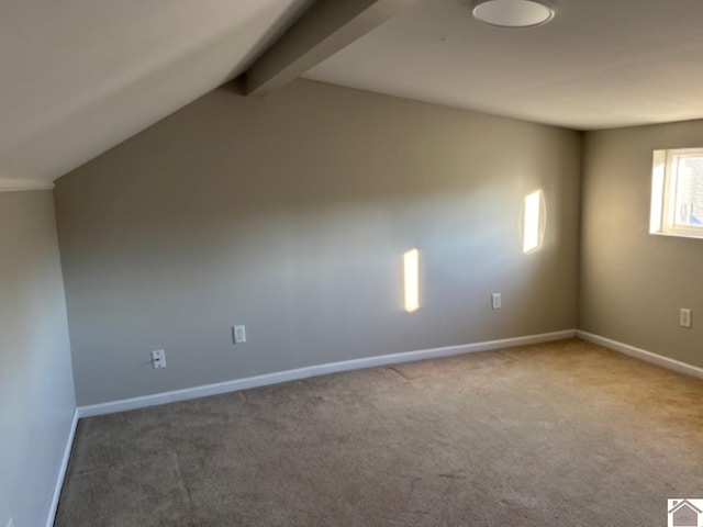 carpeted empty room featuring vaulted ceiling with beams