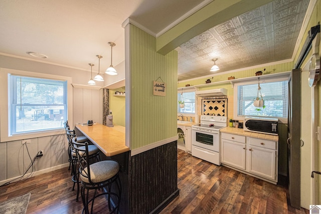 kitchen with a kitchen bar, white cabinets, dark hardwood / wood-style floors, pendant lighting, and white appliances