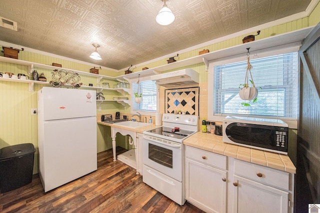 kitchen with dark hardwood / wood-style floors, pendant lighting, tile counters, white cabinets, and white appliances