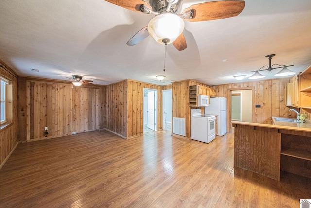 kitchen featuring sink, kitchen peninsula, white appliances, light hardwood / wood-style flooring, and wooden walls