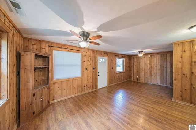 entrance foyer with a textured ceiling, light hardwood / wood-style floors, wooden walls, and ceiling fan