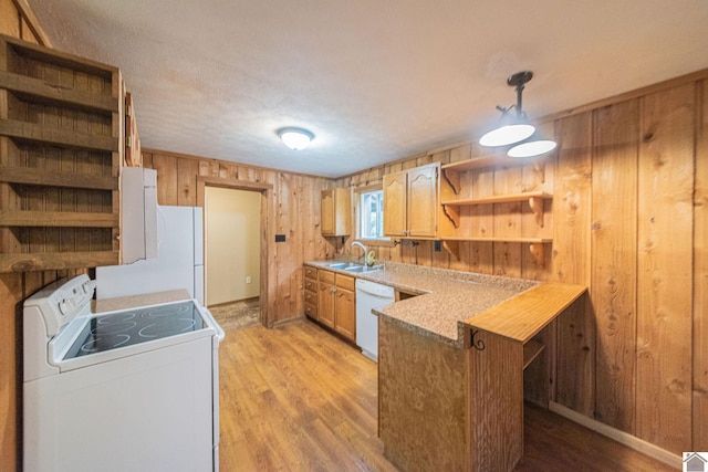 kitchen with light hardwood / wood-style floors, kitchen peninsula, hanging light fixtures, wooden walls, and white appliances