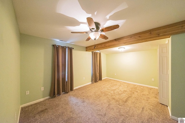 empty room featuring beamed ceiling, light colored carpet, and ceiling fan