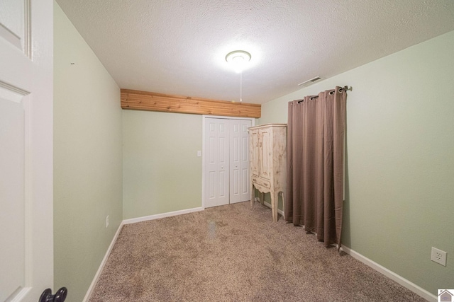 unfurnished room with carpet and a textured ceiling