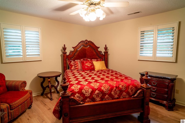 bedroom with a textured ceiling, light wood-type flooring, and ceiling fan