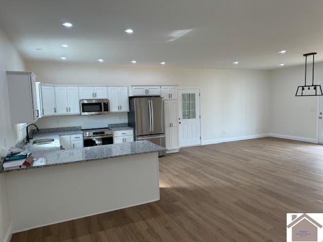 kitchen with hardwood / wood-style flooring, white cabinetry, sink, appliances with stainless steel finishes, and hanging light fixtures