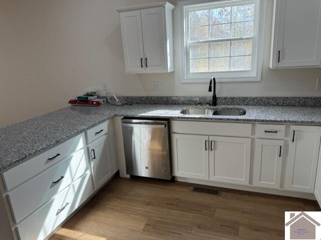 kitchen featuring light hardwood / wood-style floors, white cabinets, sink, stainless steel dishwasher, and light stone countertops