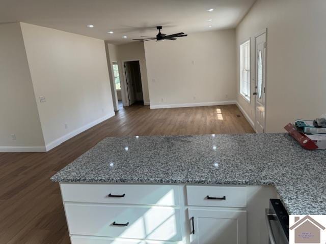 kitchen featuring dark wood-type flooring, white cabinetry, light stone countertops, and a healthy amount of sunlight