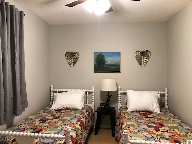 bedroom featuring a textured ceiling, ceiling fan, and wood-type flooring