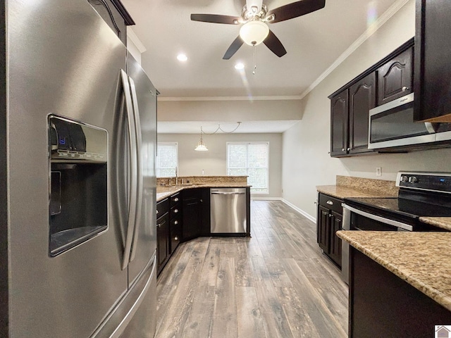 kitchen featuring stainless steel appliances, dark brown cabinets, wood-type flooring, crown molding, and pendant lighting