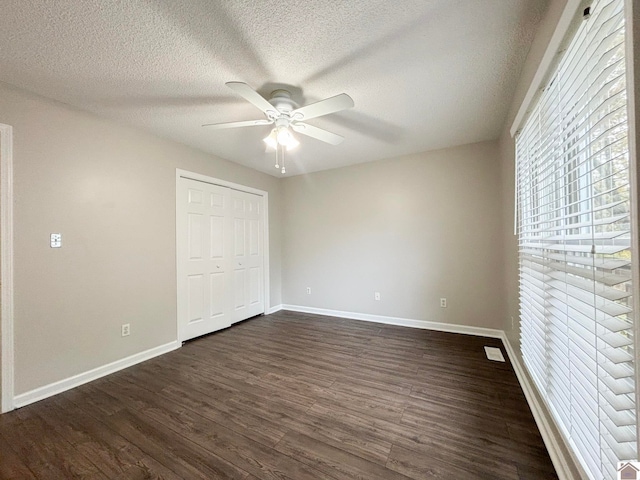 unfurnished bedroom featuring ceiling fan, a textured ceiling, a closet, and dark hardwood / wood-style flooring